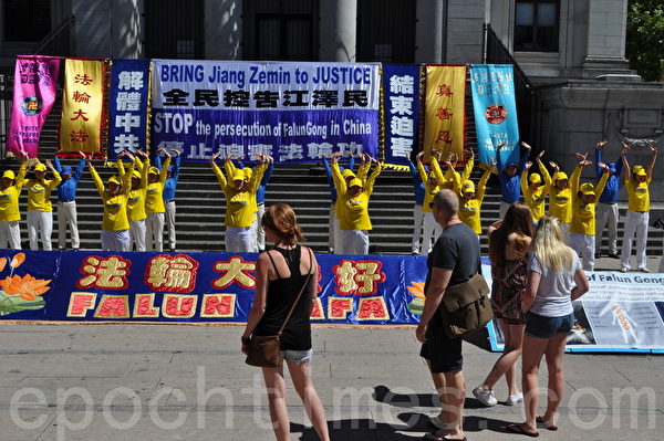 法輪功學員在「聲援全民控告江澤民」集會上煉功表演吸引路人駐足觀看。（唐風/大紀元）