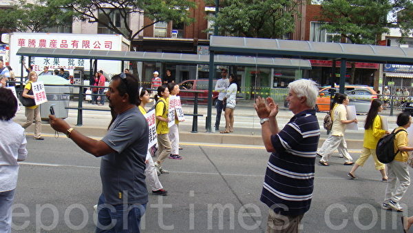 多倫多居民Joel（右邊鼓掌者）說，法輪功學員很了不起，他們是在喚醒中國人。（伊鈴／大紀元） 