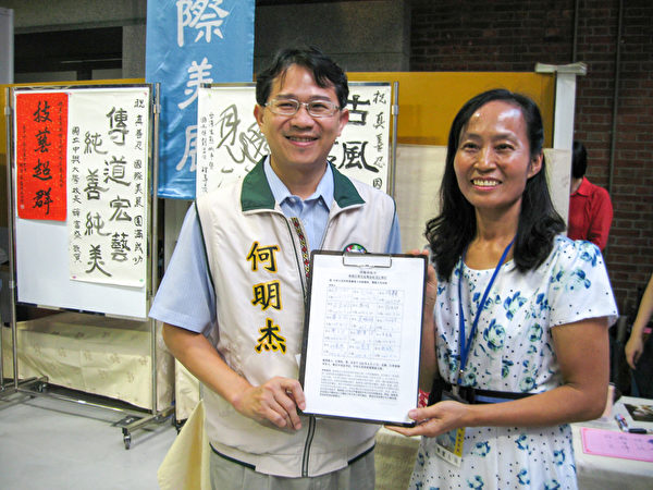 台中市议员何明杰(左)展示了他所签署的“刑事举报江泽民”联署书。(明慧网）