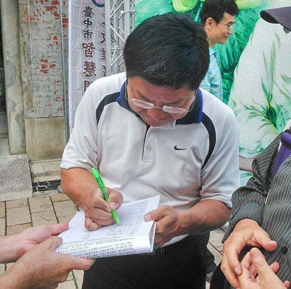 台中市文化局副局长施纯福正在“刑事举报江泽民”联署书上签名。(明慧网）