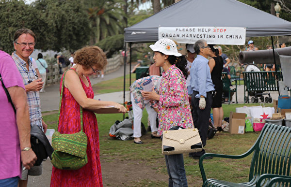 2015年9月12日，洛杉磯部分法輪功學員和民眾在南加州著名旅遊景點聖莫尼卡海灘舉行英語訴江集會，受到過往遊人的關注和支持，圖為民眾在支持訴江、反對強摘法輪功學員器官的請願書上簽名。（大紀元圖片）