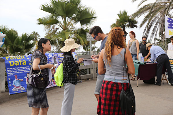 2015年9月12日，洛杉矶部分法轮功学员和民众在南加州著名旅游景点圣莫尼卡海滩举行英语诉江集会，受到过往游人的关注和支持，图为民众在支持诉江、反对强摘法轮功学员器官的请愿书上签名。（大纪元图片）