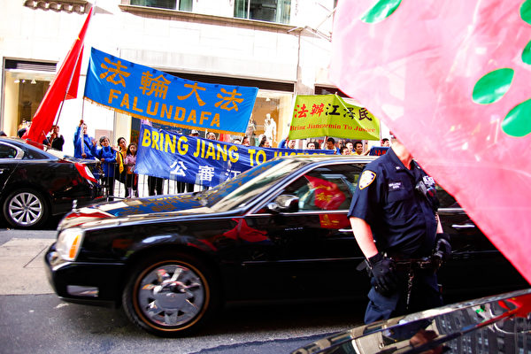 在紐約，習近平車隊經過法輪功學員打出的「法辦江澤民」等橫幅。中領館收買的親共僑團試圖遮擋。（明慧網）