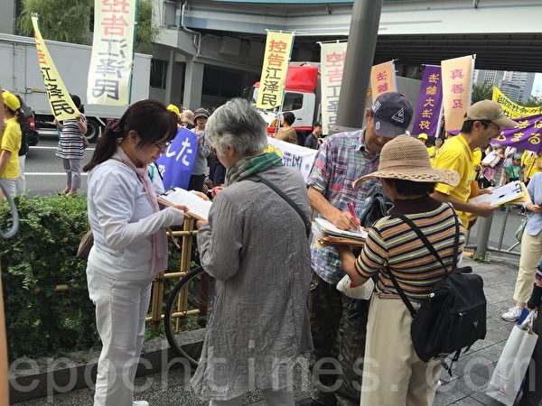 日本法轮功学员游行队伍沿途经过东京站、东银座等商业区。许多路人纷纷伸出正义之手，签名支持控告迫害元凶江泽民。（万迎杰/大纪元）