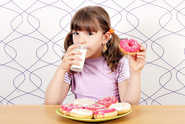 小女孩喝牛奶和吃甜甜圈。（Fotolia）　