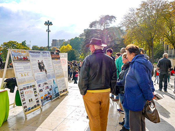 巴黎艾菲爾鐵塔下，遊客認真閱讀法輪功真相展板。（明慧網）