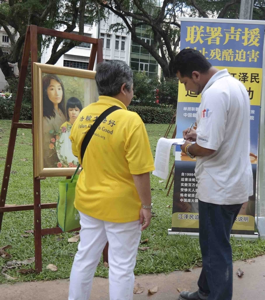 在2015年12月14日活动当天，有不少新加坡人、在新加坡工作的各国人士以及来自外国的游客在刑事举报江泽民的联署书上签名。（王秀 / 大纪元）
