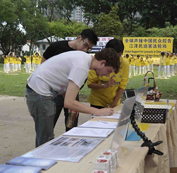 在2015年12月14日活动当天，有不少新加坡人、在新加坡工作的各国人士以及来自外国的游客在刑事举报江泽民的联署书上签名。（Peter / 大纪元）

