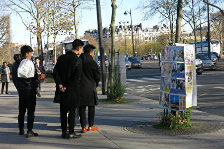 圖為巴黎鐵塔下的真相點上，大陸遊客觀看法輪功真相展版。（張宇芳/大紀元）
