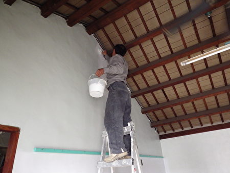65歲，手腳俐落的吳老闆，不管多高的牆他有辦法粉刷。（廖素貞／大紀元）