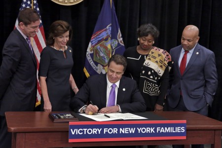 在眾人見證下，紐約州州長簽署基本工資及帶薪家庭休假法案。 (Richard Drew-Pool/Getty Images)