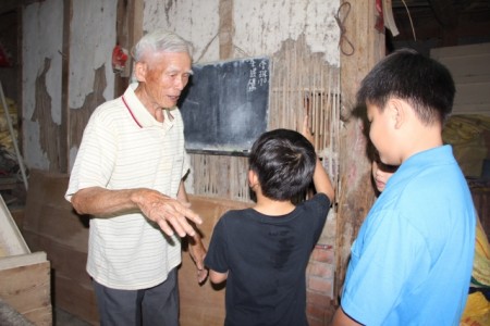 88歲徐朝魁為小朋友訴說「牛屎壁」的故事。（謝月琴／大紀元）