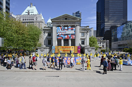 2016年5月8日，溫哥華藝術館前，法輪功學員慶賀法輪大法日，路人紛紛駐足觀看，被現場祥和美好的場面吸引。（攝影：大宇/大紀元）