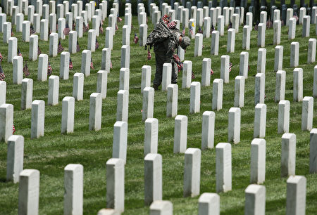 WASHINGTON, DC - MAY 26: A member of the 3rd U.S. Infantry Regiment, 'The Old Guard,' places a flag at a grave site during the 'Flags-In' ceremony May 26, 2016 at Arlington National Cemetery in Arlington, Virginia. A small American flag was placed one foot in front of more than 220,000 graves in the cemetery to mark Memorial Day. (Photo by Mark Wilson/Getty Images)