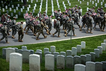 Members of the US Army march with miniature American flags to place at graves in Arlington National Cemetery on May 26, 2016 in preparation for Memorial Day in Arlington, Virginia. / AFP / Brendan Smialowski (Photo credit should read BRENDAN SMIALOWSKI/AFP/Getty Images)