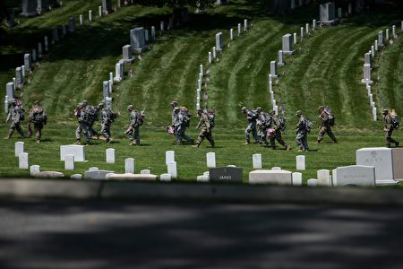 Members of the US Army walk to place American flags at graves in Arlington National Cemetery on May 26, 2016 in Arlington, Virginia in preparation for Memorial Day. / AFP / Brendan Smialowski (Photo credit should read BRENDAN SMIALOWSKI/AFP/Getty Images)