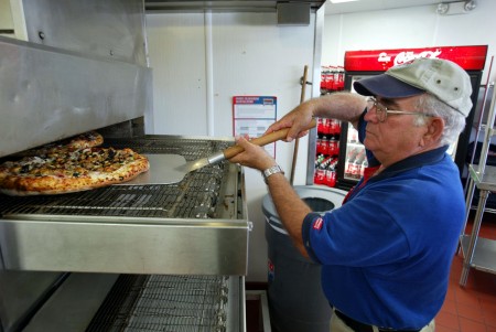 一名達美樂員工正在把烤好的披薩拿出來。