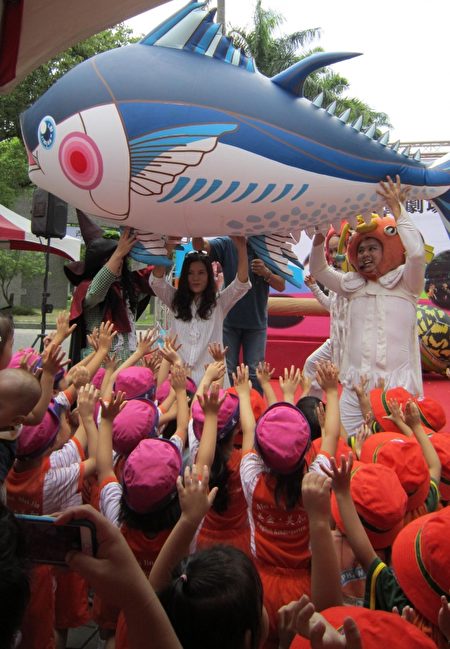 观光传播鄞处长和纸风车团员举起小黑鲔鱼气球，小朋友用手扮演水草，现场欢笑声连连。（李惠堂 /大纪元）