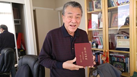 程国强教授手捧为纪念父亲程烈的一生而亲自撰写的《岁寒松柏录》一书。（邱晨/大纪元）