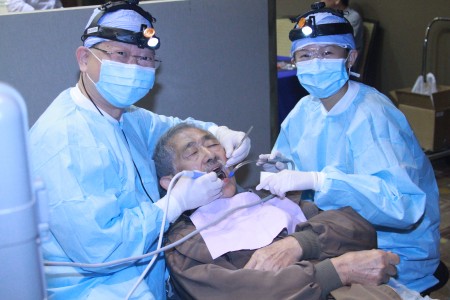 沈裕明醫師和助理在為民眾做免費洗牙。（張岳/大紀元）