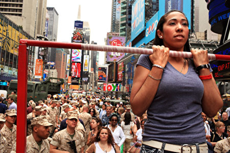 NEW YORK - MAY 28: Naomi Santiago tests her strength on a chin-up bar in front of members of the United States Marines in Times Square as part of Fleet Week festivities May 28, 2010 in New York City. Fleet Week, which has been held in New York since 1984, brings thousands of military members to the city where they engage the public with numerous activities and demonstrations, tours and contests. Fleet Week will conclude on June 2nd. (Photo by Spencer Platt/Getty Images)