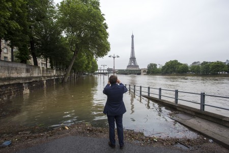 A man takes pictures of the river Seine and the Eiffel tower on June 2, 2016 on a flooded road following heavy rainfalls in Paris . Torrential downpours have lashed parts of northern Europe in recent days, leaving four dead in Germany, breaching the banks of the Seine in Paris and flooding rural roads and villages. / AFP / Geoffroy Van der Hasselt (Photo credit should read GEOFFROY VAN DER HASSELT/AFP/Getty Images)