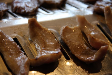 黑豬五花肉的瘦肉與脂肪堆疊層次分明，烤盤上油花迸發出吱吱聲，香氣誘人。（大紀元）