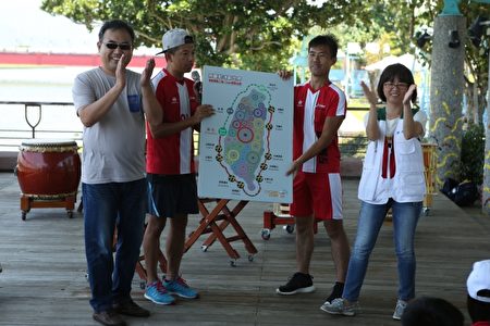 童玩節發言人張曜顯（左）與宜蘭家扶主任謝曉雯（右）在用雙腳轉動世界的台灣地圖上貼上標記。（曾漢東／大紀元）