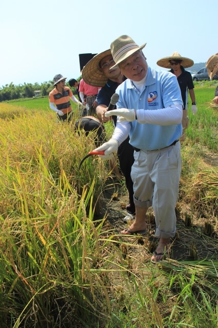 國際扶輪3490地區總監謝木土示範講解割稻方法。（謝月琴／大紀元）