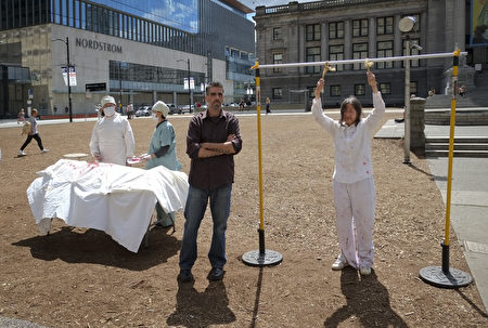 溫哥華藝術館前，法輪功學員進行活摘器官模擬演示，行人駐足觀看、攝影，希望向全世界發佈，幫助宣傳真相。（攝影：大宇/大紀元）
