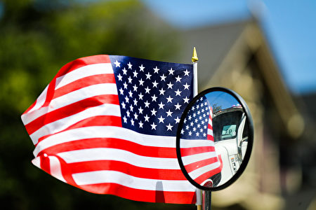 An American flag is reflected in the window of a car, as it drives through the 4th of July Parade, in Alameda, California on Monday, July 4, 2016. / AFP / GABRIELLE LURIE (Photo credit should read GABRIELLE LURIE/AFP/Getty Images)