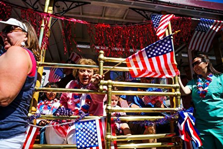 A woman on a float waves an American flag while riding through the 4th of July Parade, in Alameda, California on Monday, July 4, 2016. / AFP / GABRIELLE LURIE (Photo credit should read GABRIELLE LURIE/AFP/Getty Images)