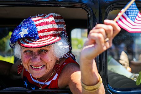 A woman waves an American flag in a car during the 4th of July Parade in Alameda, California on Monday, July 4, 2016. / AFP / GABRIELLE LURIE (Photo credit should read GABRIELLE LURIE/AFP/Getty Images)
