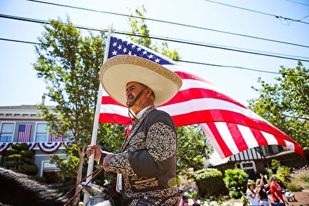A man holds an American flag as he rides a horse during the 4th of July Parade in Alameda, California on Monday, July 4, 2016. / AFP / GABRIELLE LURIE (Photo credit should read GABRIELLE LURIE/AFP/Getty Images)