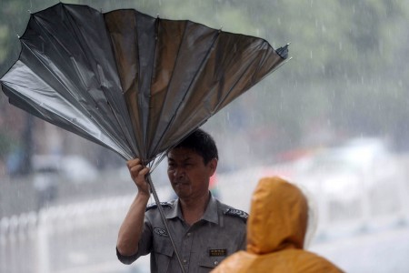 7月20日，北京男子走在街头，伞被狂风吹翻。暴雨造成至少1死34伤。 (STR/AFP/Getty Images)