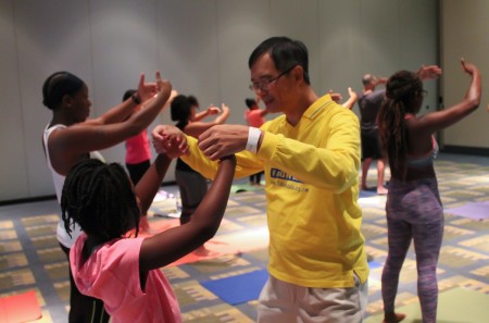 8月20日，美国一年一度的瑜伽博览会（The Yoga Expo）在首都城市华盛顿DC沃尔特.华盛顿会议中心（Walter E. Washington Convention Center）举行。在济济一堂的法轮功功法学习厅内，人们跟着台上法轮功学员范琳莎的讲解，学炼法轮功功法。（于析雨/大纪元）