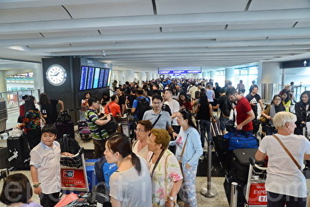 受到台风“妮妲”吹袭香港的影响，大批航班取消，今（2)日下午1点取消8号风球，机场部分飞机复飞，大批旅客为赶离港，大排长龙。(宋祥龙/大纪元）
