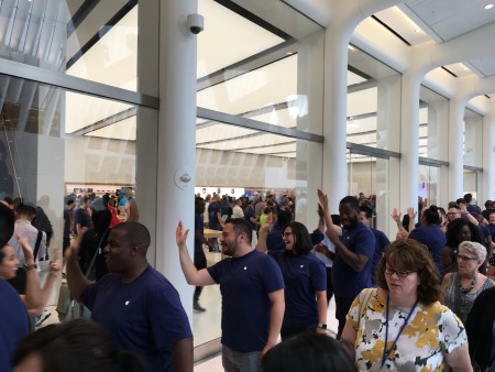 苹果员工在门口列队欢迎顾客，并和他们击掌。