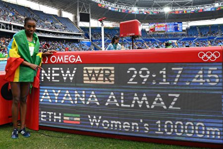 Ethiopia's Almaz Ayana celebrates next to a board displaying her new world record after the Women's 10,000m during the athletics event at the Rio 2016 Olympic Games at the Olympic Stadium in Rio de Janeiro on August 12, 2016. / AFP / FRANCK FIFE (Photo credit should read FRANCK FIFE/AFP/Getty Images)