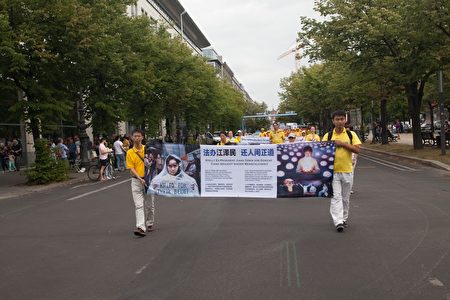  7月30日，法輪功學員在柏林舉行的大型遊行活動，圖為法輪功學員打出橫幅，揭露迫害。（Jason Wang／大紀元）