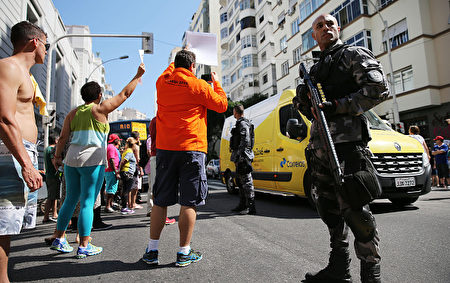 8月5日，一名持枪警察守望在巴西里约热内卢的奥运火炬传递路线上。今晚在马拉卡纳体育场举行开幕仪式，标志着2016里约奥运会正式开始。（Mario Tama/Getty Images)