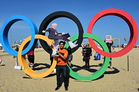 A resident of Rio de Janeiro shows a puppet depicting interim president Michel Temer in front of the Olympic Rings as he attends a demonstration against political upheaval, corruption and the cost of the Rio 2016 Olympics Games, at Copacabana beach on August 5, 2016. Thousands of Brazilians angry at political upheaval, corruption and the cost of the Rio Olympics blocked traffic in protests hours before the gala opening ceremony. Most people came to vent anger at center-right interim president Michel Temer who took power in May on the suspension of the elected leftist president, Dilma Rousseff, for an impeachment trial that her supporters claim amounts to a coup. / AFP / TASSO MARCELO (Photo credit should read TASSO MARCELO/AFP/Getty Images)