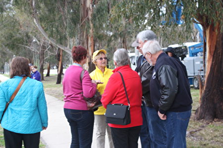 法轮功集会场面吸引了前往参观国会的澳洲游客，他们驻足观看，向法轮功学员了解真相。（骆亚／大纪元）