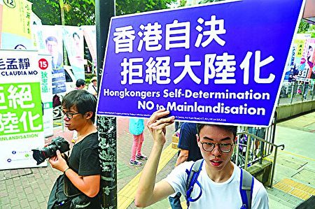 一名公民党候选人毛孟静的年轻支持者手持“香港自决 拒绝大陆化”纸牌。（宋祥龙／大纪元）