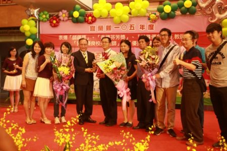 四结国小张正义校长（左6）接受县长林聪贤（左5），四结国小老师热情送花，学生在台下打鼓表示庆祝。（曾汉东／大纪元）