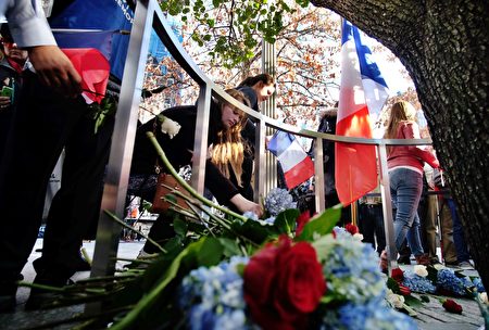 People place flowers around the Survivor Tree at the 9/11 memorial in New York on November 16, 2015, to pay their respect for the victims of the Paris terrorist attacks. A series of coordinated attacks by gunmen and suicide bombers in Paris on November 13 that killed at least 129 people and injured 352 in scenes of carnage at a concert hall, restaurants and the national stadium. AFP PHOTO/JEWEL SAMAD (Photo credit should read JEWEL SAMAD/AFP/Getty Images)