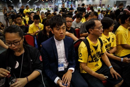 热血公民的郑松泰（左）在香港中央点票站和支持者坐在一起。 (ANTHONY WALLACE/AFP/Getty Images)