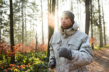 慢跑者穿着保暖衣物运行在森林冬季的一天
