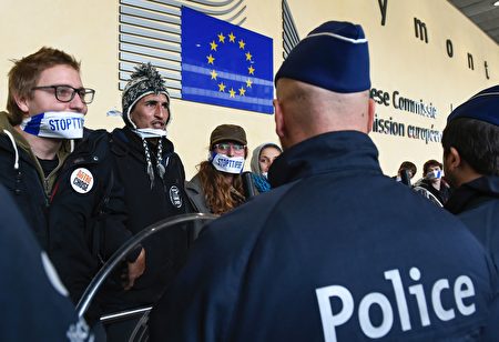 人們在布魯塞爾的歐盟總部前，抗議全球貿易造成怪獸般能力無所不及的跨國企業。（AFP）