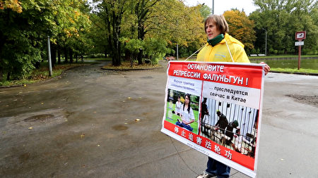 俄罗斯法轮功学员塔蒂亚娜在莫斯科中使馆前举牌抗议中共非法迫害法轮功。（新唐人）